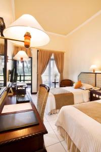 Habitación de hotel con 2 camas y escritorio en Puri Asri Hotel & Resort, en Magelang