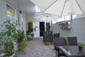 un patio con tavoli, sedie e ombrellone di Гостевой дом Лазурный a Zatoka