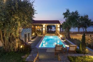 a house with a swimming pool in front of a house at By the sea luxury suites in Limenas