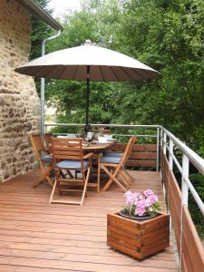 una terraza de madera con mesa y sombrilla en L'Etang, en Val Couesnon