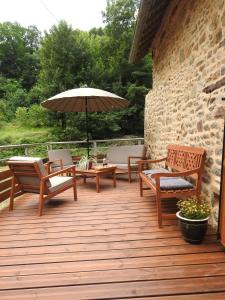 een houten terras met stoelen en een parasol bij L'Etang in Val Couesnon