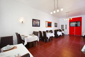 un comedor con mesas y sillas blancas y una puerta roja en Hotel Jasmin en Pforzheim