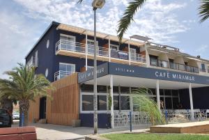 a large blue building with a cafe manufacturer sign on it at Hôtel Café Miramar in Le Grau-du-Roi