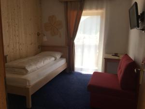 a small bedroom with a bed and a window at Garní Nëidia in Selva di Val Gardena