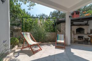 two chairs sitting on a patio with a fireplace at Apartments in Trogir in Trogir