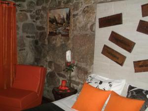 1 dormitorio con cama, silla y pared de piedra en Quinta do Pé Longo - Serra da Estrela, en Cortes do Meio