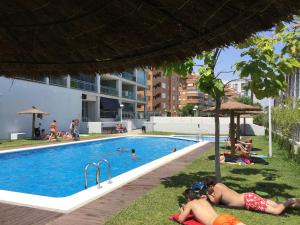 grupa ludzi leżących na trawie przy basenie w obiekcie Luxury Apartment 1ª linea de playa Marina D'Or w mieście Oropesa del Mar