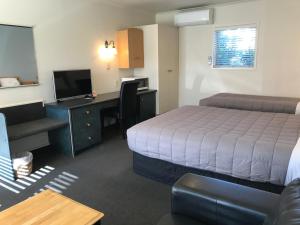 a hotel room with a bed and a desk with a computer at Pacific Harbour Motor Inn in Gisborne