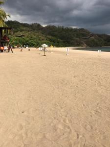 una playa de arena con sombrilla y gente en ella en Pico Beach Front Condo en Nasugbu
