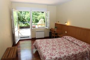 a bedroom with a bed and a large window at Hotel Metrokua in Lekeitio