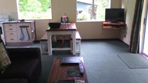 a living room with a table and a tv at Creel Lodge in Turangi