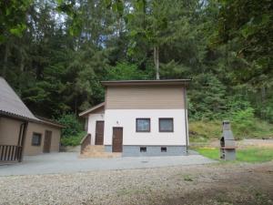 a small white and brown house with trees in the background at Mizarai Mill House in Druskininkai