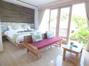 a bedroom with a bed with a purple bench and windows at Green Studio Apartment Sanur in Sanur