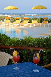 two cocktails on a table next to a swimming pool at Hotel David in Cesenatico