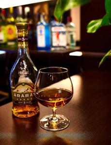 un bicchiere di cognac accanto a una bottiglia di alcol di Hotel Lilia Yerevan a Yerevan