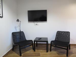 two chairs and a table with a tv on a wall at Mizarai Mill House in Druskininkai