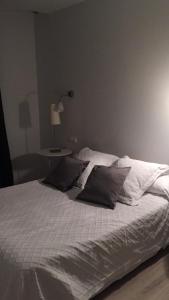 Una cama con sábanas blancas y almohadas en un dormitorio en Calle Aduana, en Madrid
