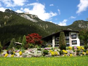 a building with flowers in front of a mountain at Haus Rofangarten in Maurach