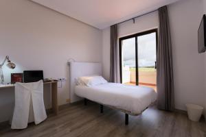 a bedroom with a bed and a desk and a window at Hospedium Hotel Castilla in Torrijos