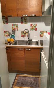 uma cozinha com um lavatório de aço inoxidável e azulejos em Eden Apartment em Anacapri