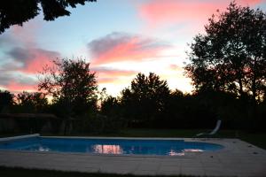 a swimming pool in a yard with a sunset at La maison de Thiré in Thiré