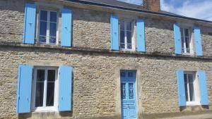 een oud stenen gebouw met blauwe luiken bij La maison de Thiré in Thiré