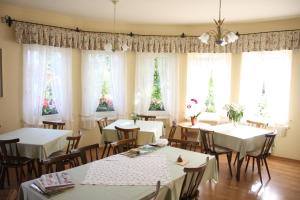 una sala da pranzo con tavoli e sedie bianchi e finestre di Haus Kärnten a Altossiach