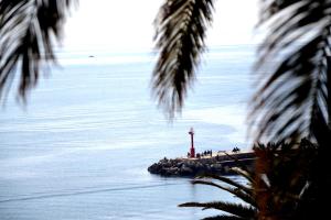 un phare sur une île dans l'eau avec des palmiers dans l'établissement Dubrovnik Stone House, à Dubrovnik