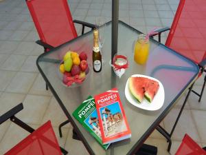 a glass table with a bowl of fruit and a drink at B&B Sweet Home Two Steps From The Ruins... in Pompei