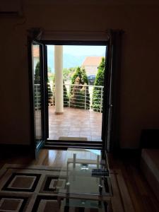 una puerta abierta a un balcón con mesa de cristal en Roman Garden Apartment en Risan