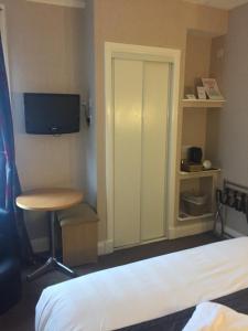 una stanza con un letto, un tavolo e una tv di Sutherland House a Oban
