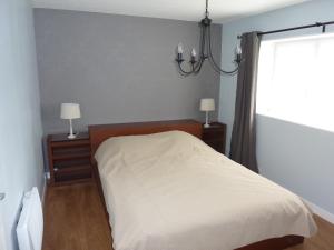 a bedroom with a bed and a window and a chandelier at Orbigny Vakantiewoningen in Saint-Pierre-la-Vieille
