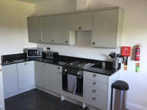 uma cozinha com armários brancos e um forno com placa de fogão em Sea View Apartments em South Shields