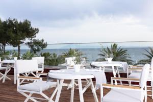 a group of tables and chairs on a deck with the ocean at Alexandra Beach Spa Resort in Potos