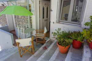 um alpendre com duas cadeiras e um guarda-sol verde em Dolichi Studio em Samos