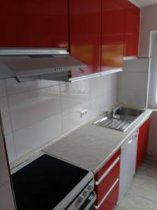 a small kitchen with red cabinets and a sink at Ferienwohnung Peter Hofling in Wertheim