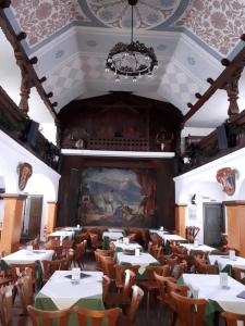 ein Esszimmer mit Tischen, Stühlen und einem Gemälde in der Unterkunft Gasthof zum Rassen in Garmisch-Partenkirchen