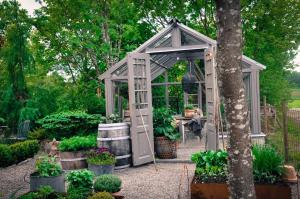 a greenhouse in a garden with potted plants at Håkesgård Bed&Garden in Veddige