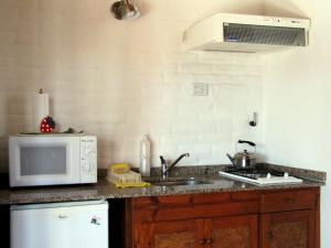 a kitchen with a sink and a microwave at Costa Serrana Apart Hotel in Mina Clavero