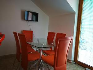 una sala da pranzo con tavolo in vetro e sedie rosse di Apartment Babovic Orahovac Kotor a Kotor (Cattaro)