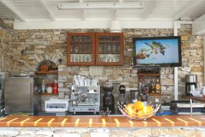 a kitchen with a stone wall and a tv at Villa Antoniadis in Platis Gialos