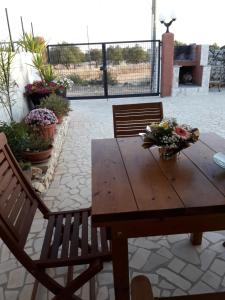 un tavolo in legno con due sedie e fiori su un patio di Bilocale jasmin a Corsano