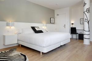 a white bedroom with a large white bed and a zebra rug at Hotel Flysch in Zumaia
