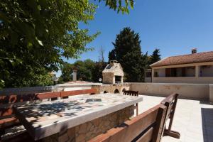 a patio with a stone wall and a table and benches at Apartmani Antonella in Premantura