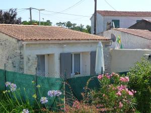 a house behind a fence with flowers in front of it at Maisonette de pays classée 3 étoiles in La Cotinière