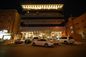 a parking lot with cars parked in front of a building at Elaf Aparthotel in Buraydah