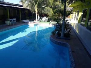 阿魯阿南的住宿－水瓶座旅館，一座种植了棕榈树的蓝色游泳池,位于酒店大楼旁