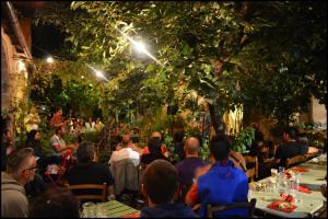 een groep mensen die 's nachts aan tafel in een tuin zitten bij Antica Dimora Del Gruccione, Albergo diffuso in Santu Lussurgiu