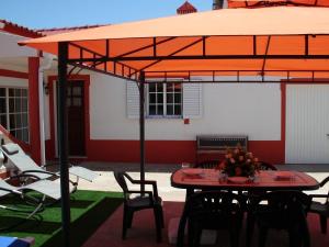 a table and chairs under an orange umbrella on a patio at Moradia perto dos Palmares in Lagos