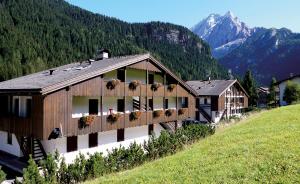 a building on a hill with mountains in the background at Residence Casa Canazei in Canazei